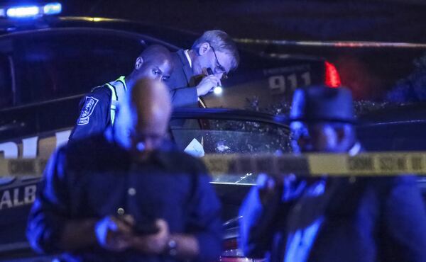 DeKalb County police Sgt. B. Danner (with flashlight) examines the bullet holes in a car where a man was shot and killed early Thursday, Feb. 22, 2018, in DeKalb County. Nicholas Bankston was returning home following his own birthday celebration when he was shot and killed, according to neighbors. His children and two other adults were also in the car, but none were injured. (JOHN SPINK/JSPINK@AJC.COM)