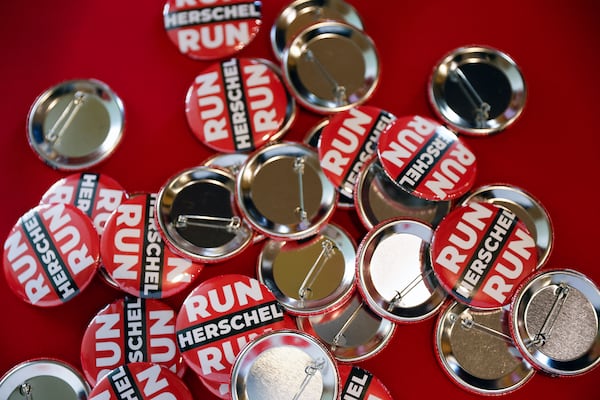 “Run Herschel Run” pins sit on a table at a campaign event for Republican U.S. Senate candidate Herschel Walker in Rome, Georgia, on Oct. 24, 2022. (Natrice Miller/AJC)  