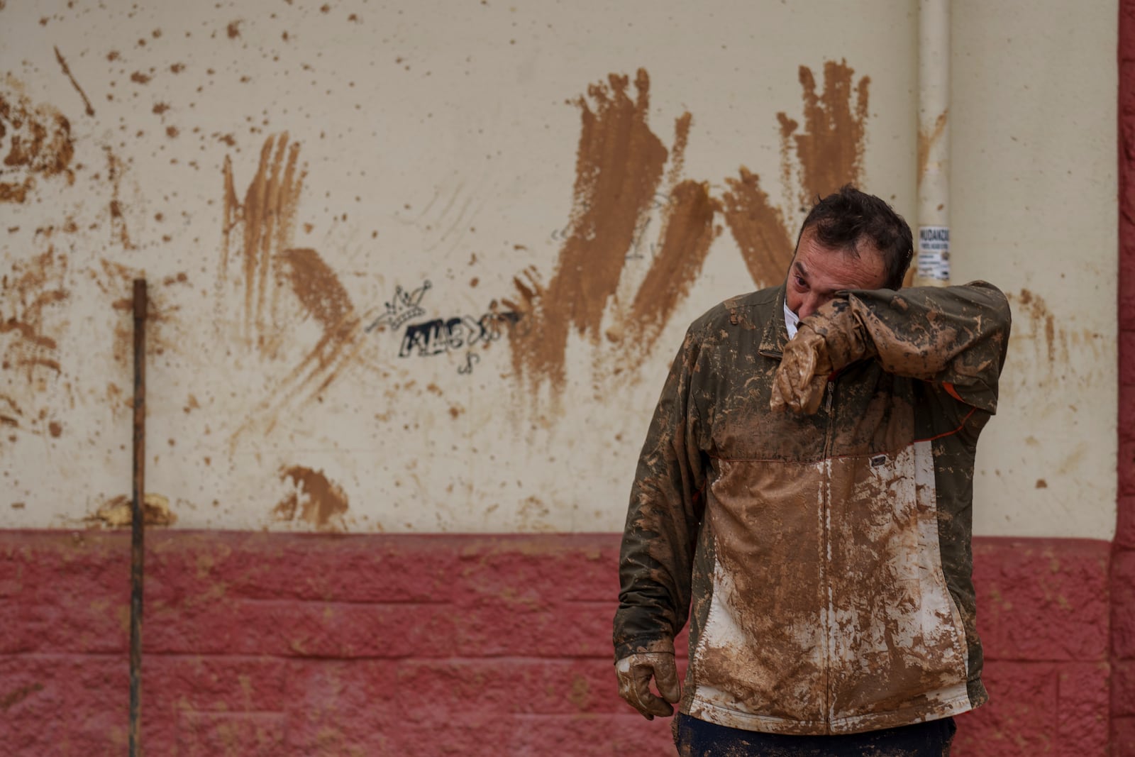 A man wipes mud off his face in an area affected by floods in Catarroja, Spain, on Monday, Nov. 4, 2024. (AP Photo/Manu Fernandez)