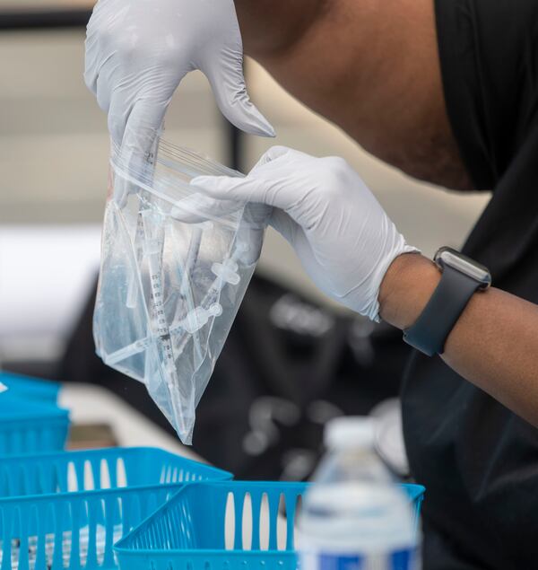 A medical worker places Pfizer vaccination shots in a bag for storage in a cooler at an IRC and CORE drive-thru vaccination site located at the East Lake YMCA in Atlanta Tuesday. (Alyssa Pointer / Alyssa.Pointer@ajc.com)