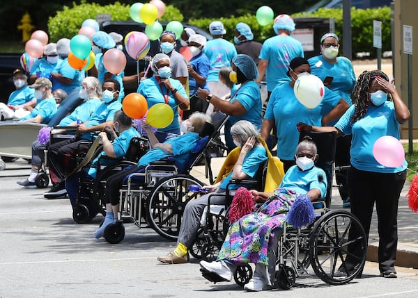 Residents and staff line the curb fin May for the start of a community parade celebrating residents who have survived COVID-19 at Westbury Medical Care & Rehab in Jackson. Family members and supporters decorated vehicles with signs and posters and for many it was the first opportunity to see their loved ones in months. Curtis CURTIS COMPTON / CCOMPTON@AJC.COM