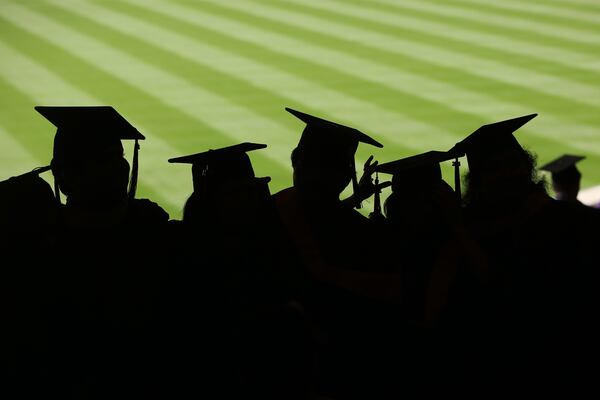 Graduates stand together before the start of commencement exercises for New York University at Yankee Stadium in New York, May 21, 2014. The pay gap between college graduates and everyone else rose to a record high last year, suggesting there are too few graduates. (Michael Appleton/The New York Times)