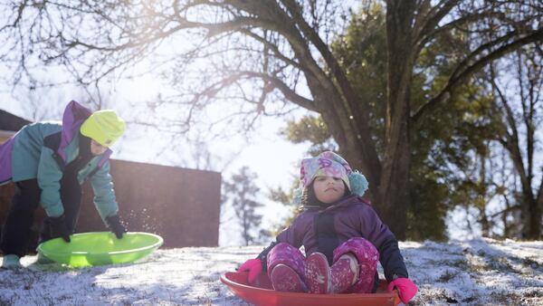 Marcy Ringel, 4, right, slides down a snow covered hill as her older sister, Lucy Ringel, 8, left, prepares to follow in Dunwoody on Thursday. ALYSSA POINTER/ALYSSA.POINTER@AJC.COM