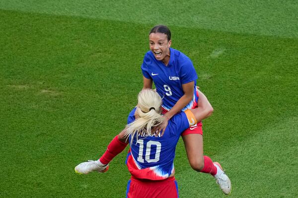 Mallory Swanson leaps into teammate Lindsey Horan's arms.