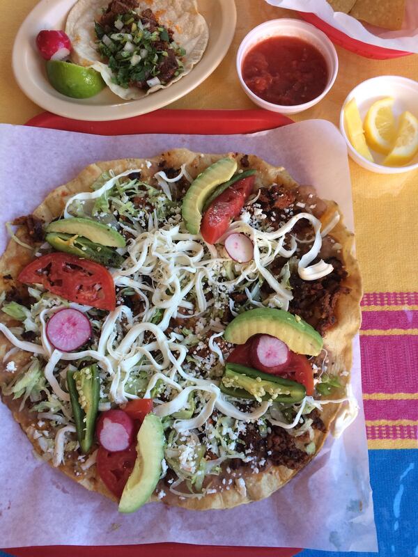 Tlayudas are an Oaxacan specialty at Taqueria La Oaxaqueña in Jonesboro. This one is topped with chorizo and al pastor meat. A cabeza taco is at upper left. CONTRIBUTED BY WENDELL BROCK