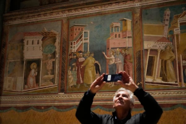 A visitor scans with his smartphone Giotto's frescoes inside St. Francis Basilica in Assisi, Italy, Saturday, March 1, 2025. (AP Photo/Gregorio Borgia)