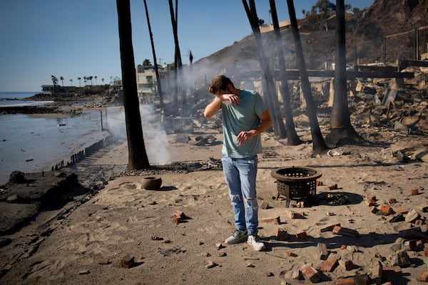 Luke Dexter reacts as he sifts through the remains of his father's fire-ravaged beach front property in the aftermath of the Palisades Fire Friday, Jan. 10, 2025 in Malibu, Calif. (AP Photo/John Locher)