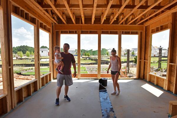 Spenser and Cory Hewett check the construction of their new house as Cory holds his 15-month-old son Eliot in the Pinewood Forest community in Fayetteville on Saturday, June 22, 2019. Spenser and Cory Hewett are millennials who have left their life in Buckhead for Fayette County, metro Atlanta’s oldest county by age. HYOSUB SHIN / HSHIN@AJC.COM