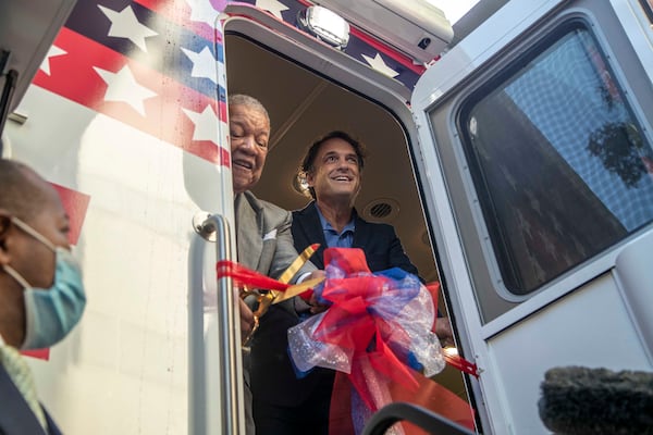 10/1/2020 - Atlanta, Georgia - Fulton Commission Chairman Robb Pitts (left) and Fulton County Director of Registration and Elections Richard Barron (right) cut a ceremonial ribbon for a new Fulton County mobile voting bus in downtown Atlanta, Thursday, October 1, 2020.  (Alyssa Pointer / Alyssa.Pointer@ajc.com)