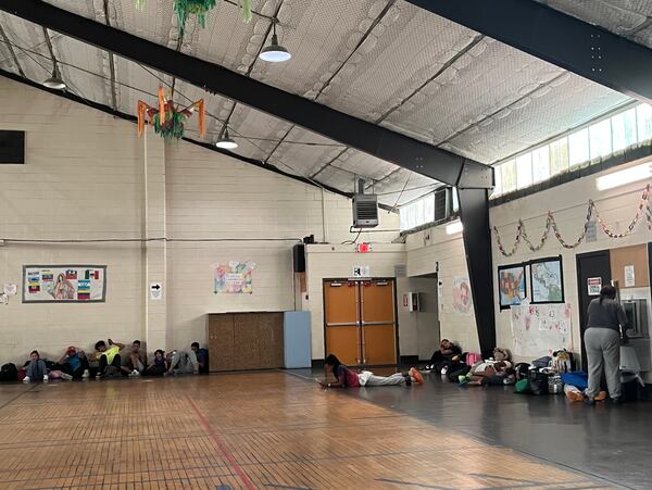 Migrants sit on the ground of a gymnasium inside Sacred Heart Church's migrant shelter in El Paso, Texas on Friday, June 7, 2024. (Lautaro Grinspan)