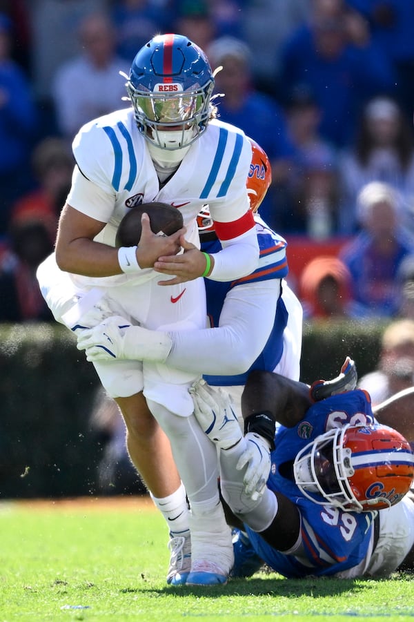 Mississippi quarterback Jaxson Dart, front, is sacked by Florida defensive lineman Caleb Banks, center, and defensive lineman Cam Jackson (99) during the first half of an NCAA college football game, Saturday, Nov. 23, 2024, in Gainesville, Fla. (AP Photo/Phelan M. Ebenhack)