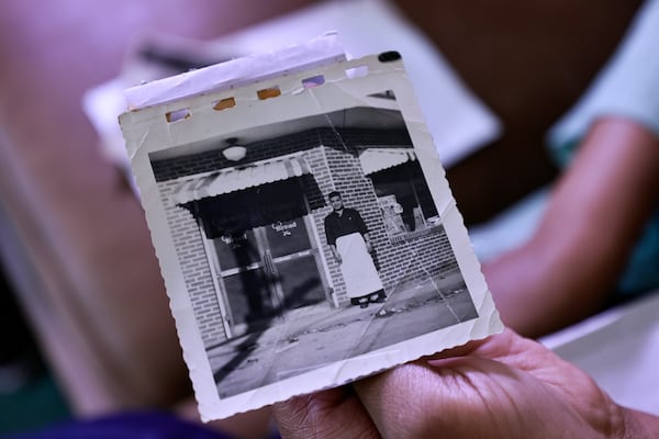 Yolanda Mullins holds up a photo of her grandfather Charlie Hunter Sr. in front of his store. (Natrice Miller/natrice.miller@ajc.com)