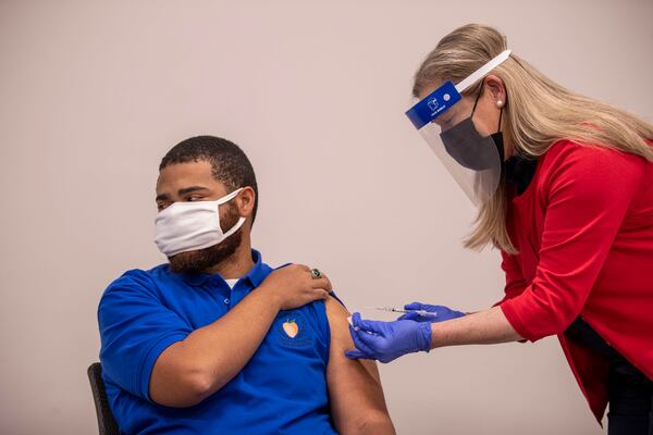 Marty Carpenter, Jr., Gwinnett, Rockdale and Newton County Health Department HIV Program Manager, is shown here receiving the COVID-19 Pfizer BioNTech vaccination, apparently the first one administered in metro Atlanta.  The department's director, Dr. Audrey Arona, gave him the shot.  The health department received 2,000 Pfizer vaccine doses for distribution in the three counties, part of about 16,000 doses received in metro Atlanta Wednesday. (PHOTO by Alyssa Pointer / Alyssa.Pointer@ajc.com)