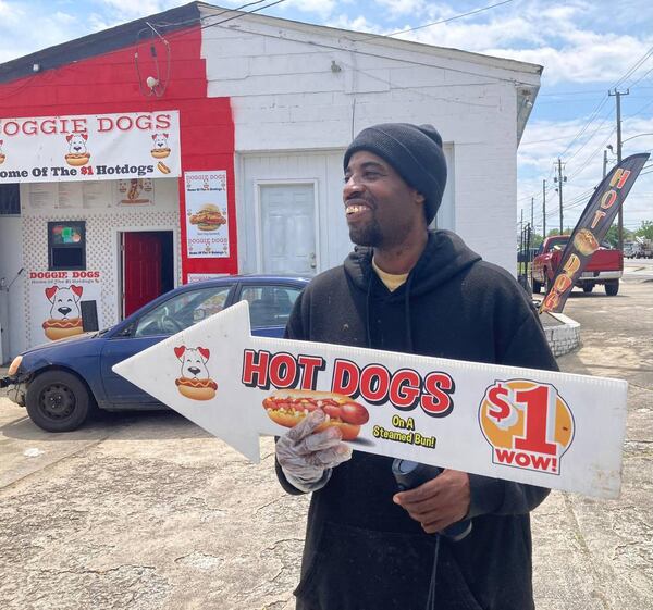 In this Telegraph photo taken in April, Doggie Dogs owner Tony Walker outside his walk-up hot dog joint off Pio Nono Avenue in Macon with a sign offering plain hot dogs for $1. (Photo Courtesy of Becky Purser/The Telegraph)