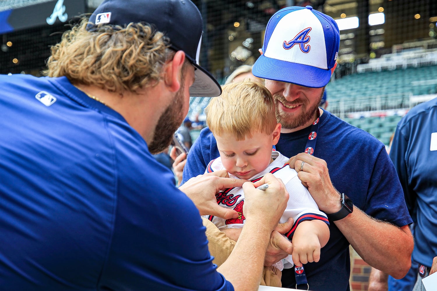 Atlanta Braves player A.J Minter, (left), signs a shirt of a young fan before the game against the Tampa Bay Rays at Truist Park in Atlanta, Georgia  on Friday, June 14, 2024.   (Ziyu Julian Zhu / AJC)