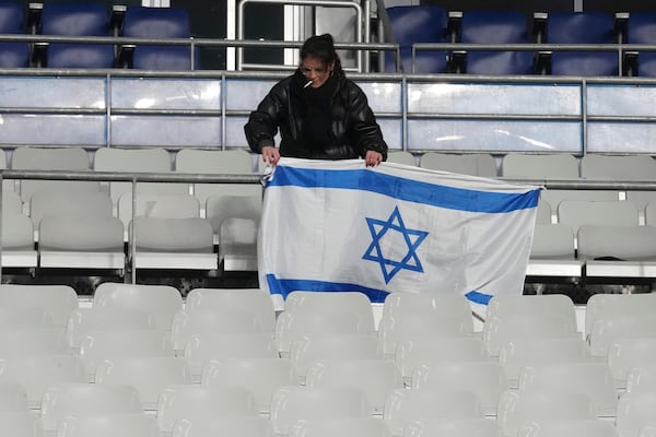 A woman adjusts an Israeli flag before the UEFA Nations League soccer match between France and Israel at the Stade de France stadium in Saint-Denis, outside Paris, Thursday Nov. 14, 2024. (AP Photo/Michel Euler)