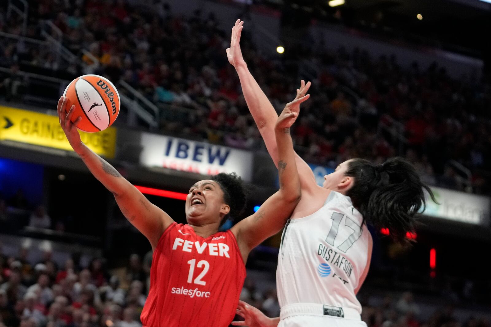 Indiana Fever's Damiris Dantas (12) shoots against Las Vegas Aces' Megan Gustafson (17) during the first half of a WNBA basketball game, Wednesday, Sept. 11, 2024, in Indianapolis. (AP Photo/Darron Cummings)