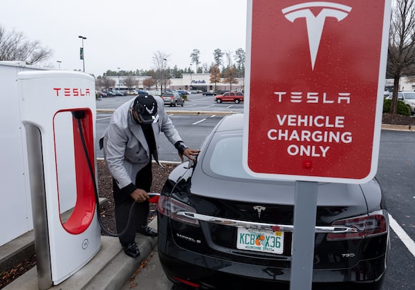 Craig Clayton, Sr., plugs a rental Tesla into a charger at Camp Creek Marketplace in East Point on Friday Dec. 10, 2021. Clayton rented the car for a trip from Florida to Atlanta because he is interested in buying one and wanted to see what it was like to take a road trip in an electric car. One issue he found was having to go out of his way to find fast chargers.  (Ben Gray for the Atlanta Journal-Constitution)