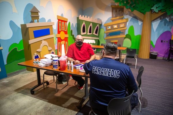 Paramedics Jonathan Cusick and Paul Long wait for people to show up to get their COVID-19 shot in the children's room of the Impact Church in Atlanta. (Steve Schaefer for The Atlanta Journal-Constitution)