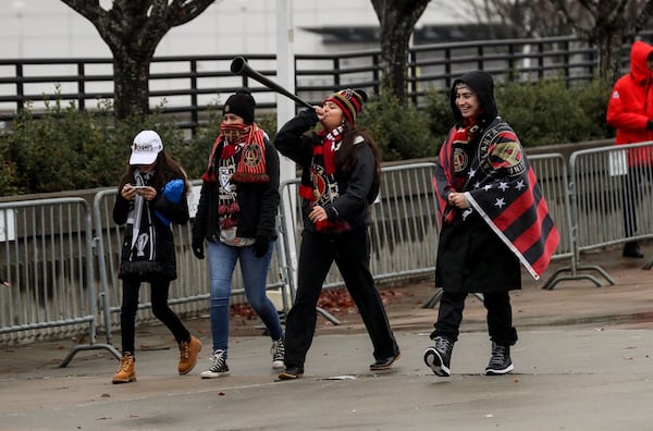 Wearing the team colors, Atlanta United fans begin to arrive 9 a.m. Monday at the Home Depot Backyard for a pep rally and celebration of the MLS Championship win. (Alyssa Pointer/AJC)