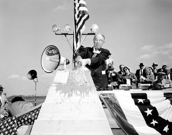 Atlanta Mayor William B. Hartsfield dedicates the Buford Dam on Oct. 9, 1957, by crashing a Coca-Cola bottle against a platform. (Lane Bros. Commercial Photographers / GSU Library LBME1-026c)