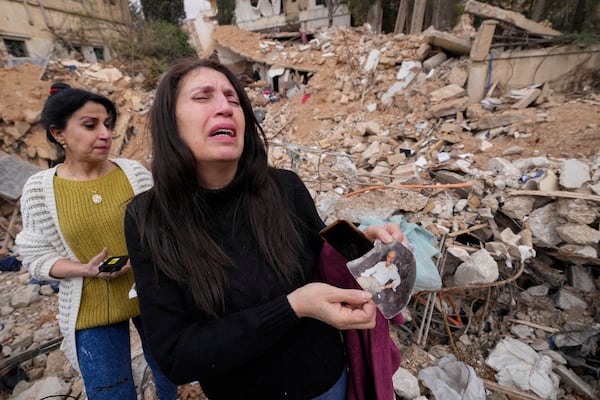 Zeina Rida Jawhari, reacts after recovering a photo of her father from the rubble of her destroyed house in Baalbek, eastern Lebanon, Thursday, Nov. 28, 2024. (AP Photo/Hassan Ammar)