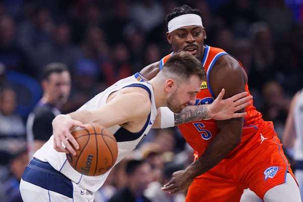 Dallas Mavericks guard Luka Doncic, left, drives against Oklahoma City Thunder guard Luguentz Dort (5) during the first half of an Emirates NBA Cup basketball game, Tuesday, Dec. 3, 2024, in Oklahoma City. (AP Photo/Nate Billings)