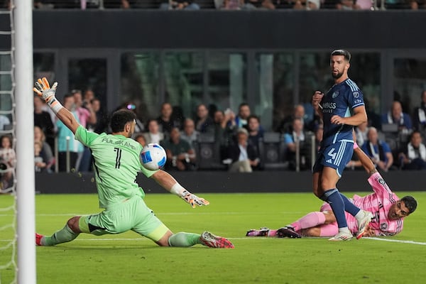 Inter Miami forward Luis Suarez, right, scores past Sporting Kansas City goalkeeper John Pulskamp (1) and defender Robert Voloder (4) during the first half of a CONCACAF Champions Cup soccer match, Tuesday, Feb. 25, 2025, in Fort Lauderdale, Fla. (AP Photo/Rebecca Blackwell)