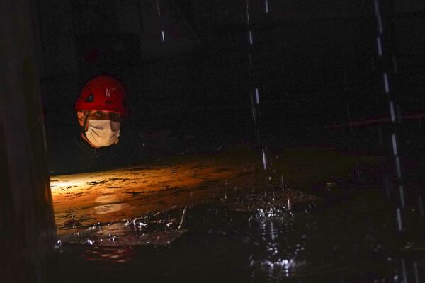 A Civil Guard walks in a flooded indoor car park to check cars for bodies after floods in Paiporta, near Valencia, Spain, Monday, Nov. 4, 2024. (AP Photo/Alberto Saiz)