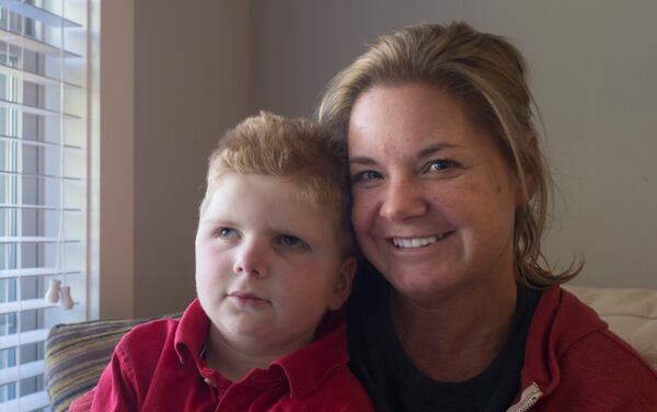 Tripp Halstead, 7, and Stacy Halstead pose for a portrait last month in their home in Jefferson, Ga. Tripp, who suffered a traumatic brain injury five years ago when a tree limb fell on him at his day care, was rushed to the hospital Monday. He was expected to retrun home Wednesday. (CASEY SYKES, CASEY.SYKES@AJC.COM)