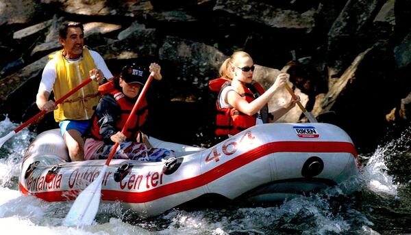 A smiling Horace Holden Sr. guides two clients through whitewater for the Nantahala Outdoor Center. Holden, who owned Camp Chattahoochee in Roswell for many years, also co-founded the Georgia Canoeing Association and the Nantahala Outdoor Center.