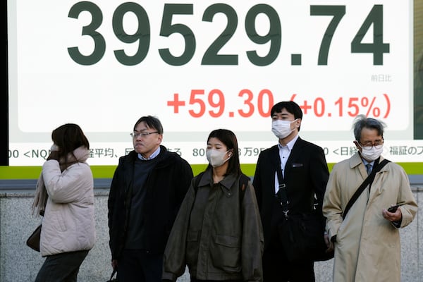 People stand in front of an electronic stock board showing Japan's Nikkei index at a securities firm Monday, Dec. 16, 2024, in Tokyo. (AP Photo/Eugene Hoshiko)