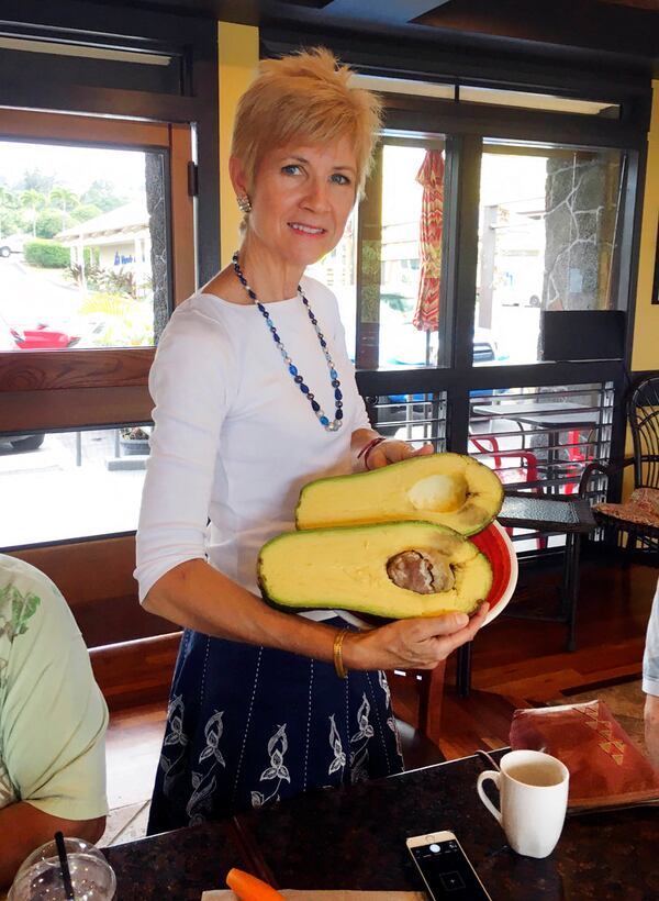 FILE - In this Nov. 28, 2017 file photo provided by Mary Lou Knurek, Pamela Wang poses for a photo in Kealakekua, Hawaii, with an avocado she found while on a walk. Guinness World Records has confirmed that Wang found the world's heaviest avocado, weighing 5-pound, 3.6-ounce (2.4-kilogram).  (Mary Lou Knurek via AP, File)