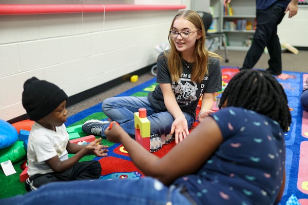 Eighth grade student Grace Polzin plays with 3-year-old Zion Blackman next to his mother Sheldon Blackman at the Play 2 Learn program at Duluth Middle School, Wednesday, Nov. 8, 2023, in Duluth. These students are part of the teaching profession program and have an interest in a career in education. (Jason Getz / Jason.Getz@ajc.com)