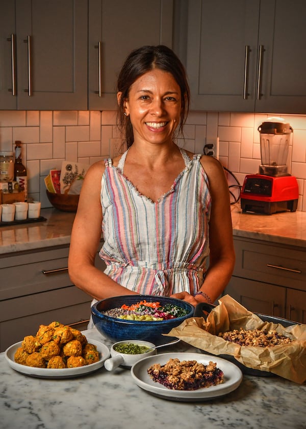 Atlanta registered dietitian nutritionist Nichole Dandrea-Russert poses in her home kitchen with her dishes (from left) Cauliflower Chickpea Curry Bites with Mint Chutney (in small bowl), Grains, Greens and Beets Bowl with Creamy Citrus Dressing and Deep South Blueberry Cobbler. (Styling by Nichole Dandrea-Russert / Chris Hunt for the AJC)