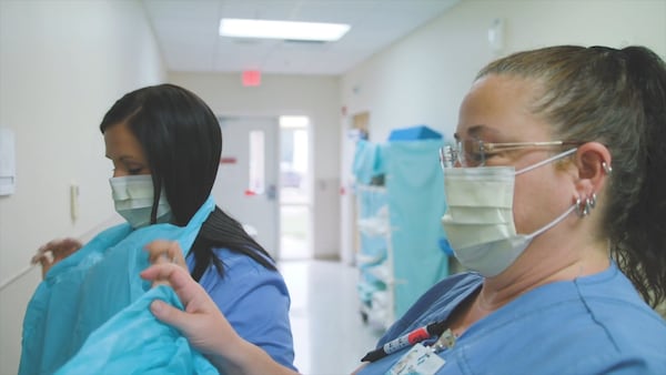 Nurses Amber Townsend and Rebecca Brown of the Hospital Authority of Miller County put on their personal protective equipment before entering a patient room. (Michael Wise/The Big Picture)