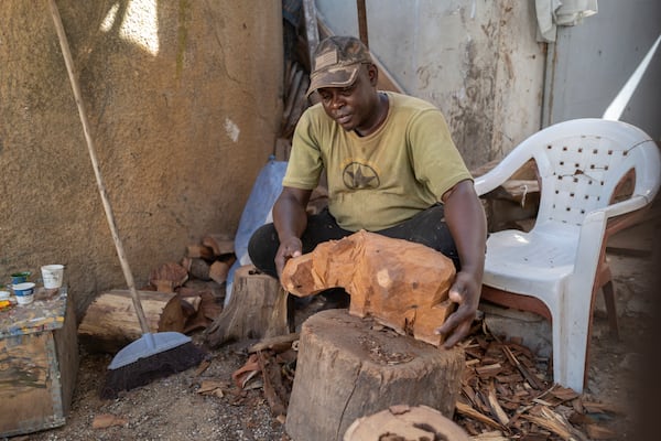 Woodcarver Papis Kanté sculpts a wooden hippopotamus to be exhibited in the "Rebondir" exhibition as part of the Dakar 2024 Biennial Off in Dakar, Senegal, Thursday, Nov. 28, 2024. (AP Photo/Sylvain Cherkaoui)