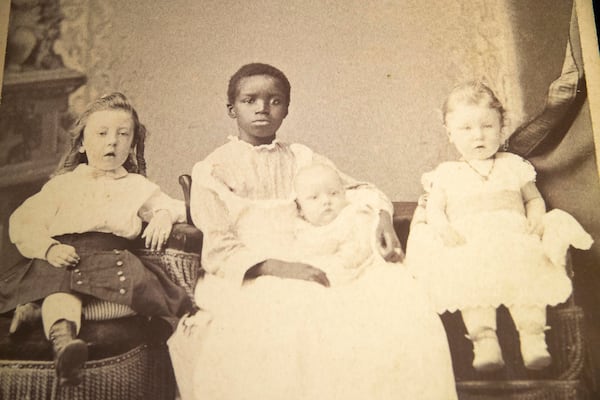 In one photo from the ‘Framing Shadows’ exhibit, a black girl, perhaps no older than 13 years old, holds onto a white toddler just old enough to stand. 