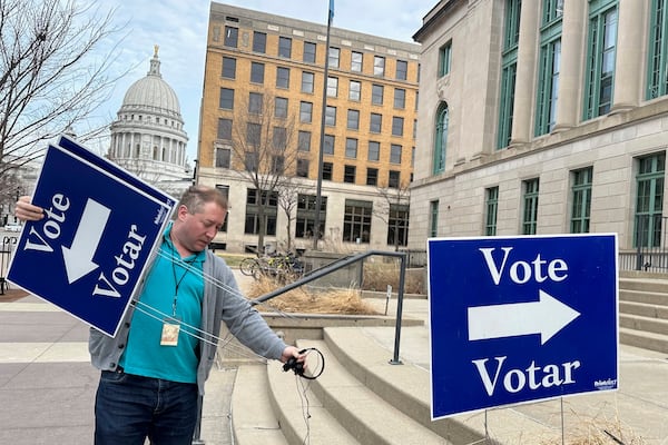 Election worker Mike Quieto with the city of Madison puts out voting signs near the state Capitol ahead of polls opening for the first day of early voting in the race for state Supreme Court on Tuesday, March 18, 2025, in Madison, Wis. (AP Photo/Scott Bauer)