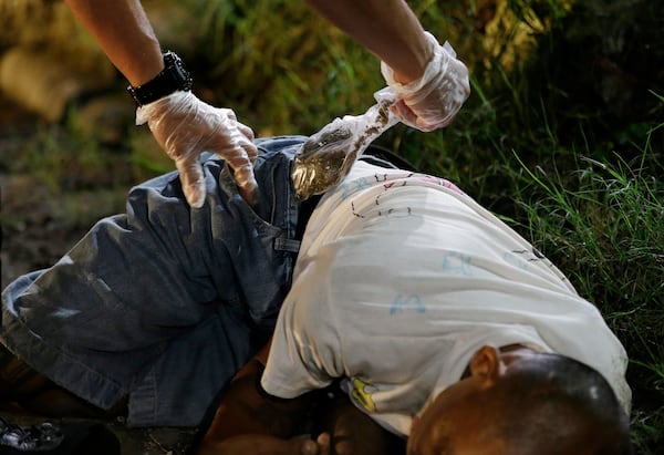 FILE- A police officer takes out a bag of Marijuana from the pocket of one of two unidentified drug suspects after they were shot dead by police as they tried to evade a checkpoint in Quezon city, north of Manila, Philippines, Sept. 6, 2016. (AP Photo/Aaron Favila, File)