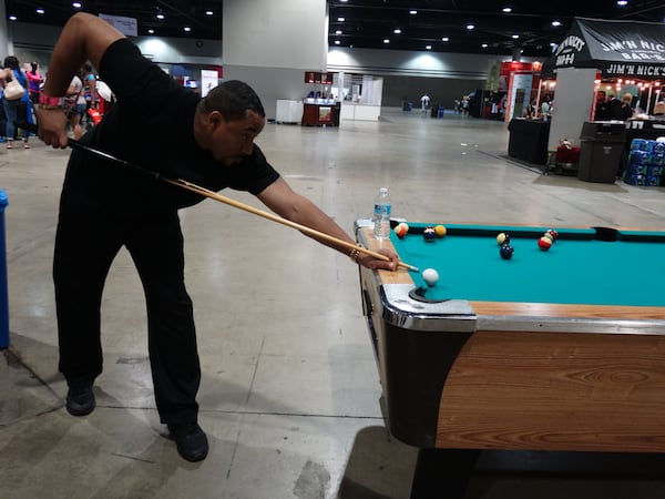 Jusson Blackstock of Atlanta takes a break from working a booth for a quick game of pool. CREDIT: Rodney Ho/ rho@ajc.com