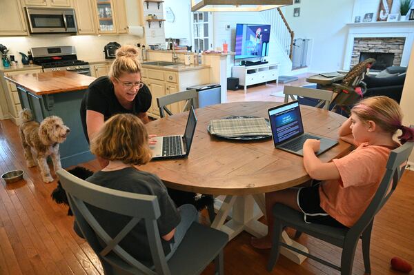 Caitlin Snyder reacts as she helps her two daughters Ryleigh (left), 10, and Zoie, 9, while they are being homeschooled on Wednesday, Aug. 25, 2021. The parents pulled them out of Kemp Elementary in Cobb County because the district has no mask mandate and they could not enroll in virtual classes. (Hyosub Shin / Hyosub.Shin@ajc.com)