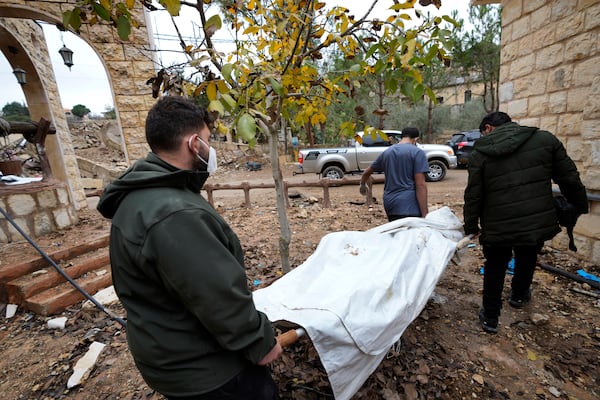 Lebanese men carry a dead body retrieved from under the rubble of a destroyed house in Ainata village, southern Lebanon, following a ceasefire between Israel and Hezbollah that went into effect on Wednesday, Nov. 27, 2024. (AP Photo/Hussein Malla)