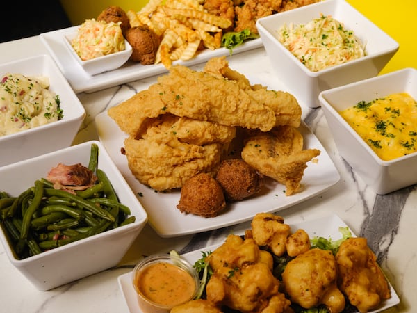 Fried pollock with hushpuppies, surrounded by an assortment of side dishes, from the kitchen of Bankhead Seafood, the reopened and reimagined Westside restaurant owned by Atlanta rappers T.I. and Killer Mike.