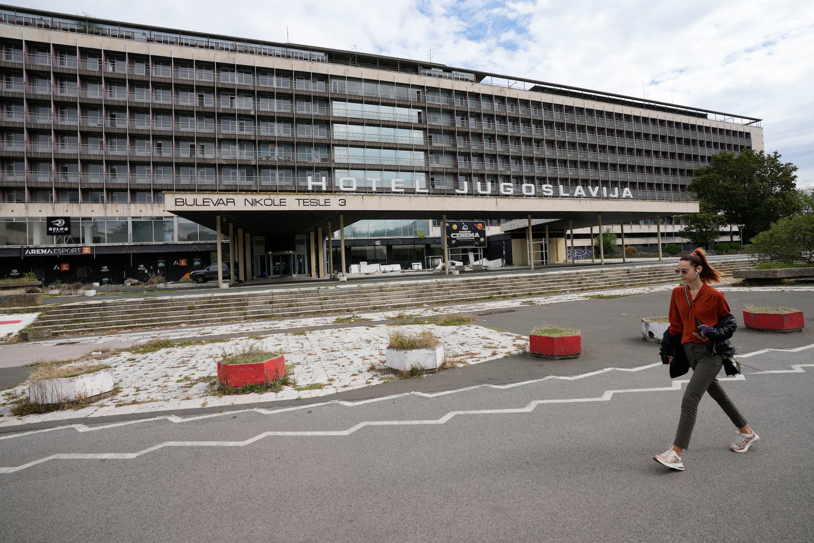 A woman walks past Hotel Yugoslavia, once a symbol of progress in the former socialist state of Yugoslavia that broke apart in the 1990s and a favorite gathering place for local residents as well as world leaders, in Belgrade, Serbia, Thursday, Oct. 3, 2024. (AP Photo/Darko Vojinovic)