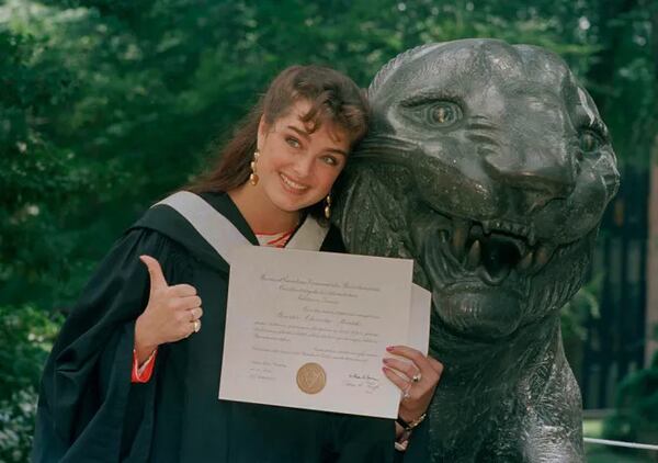 Actress Brooke Shields gives the thumbs-up in her cap and gown as she shows her diploma during graduation ceremonies at Princeton University. She graduated from the New Jersey institute in 1987.  AP