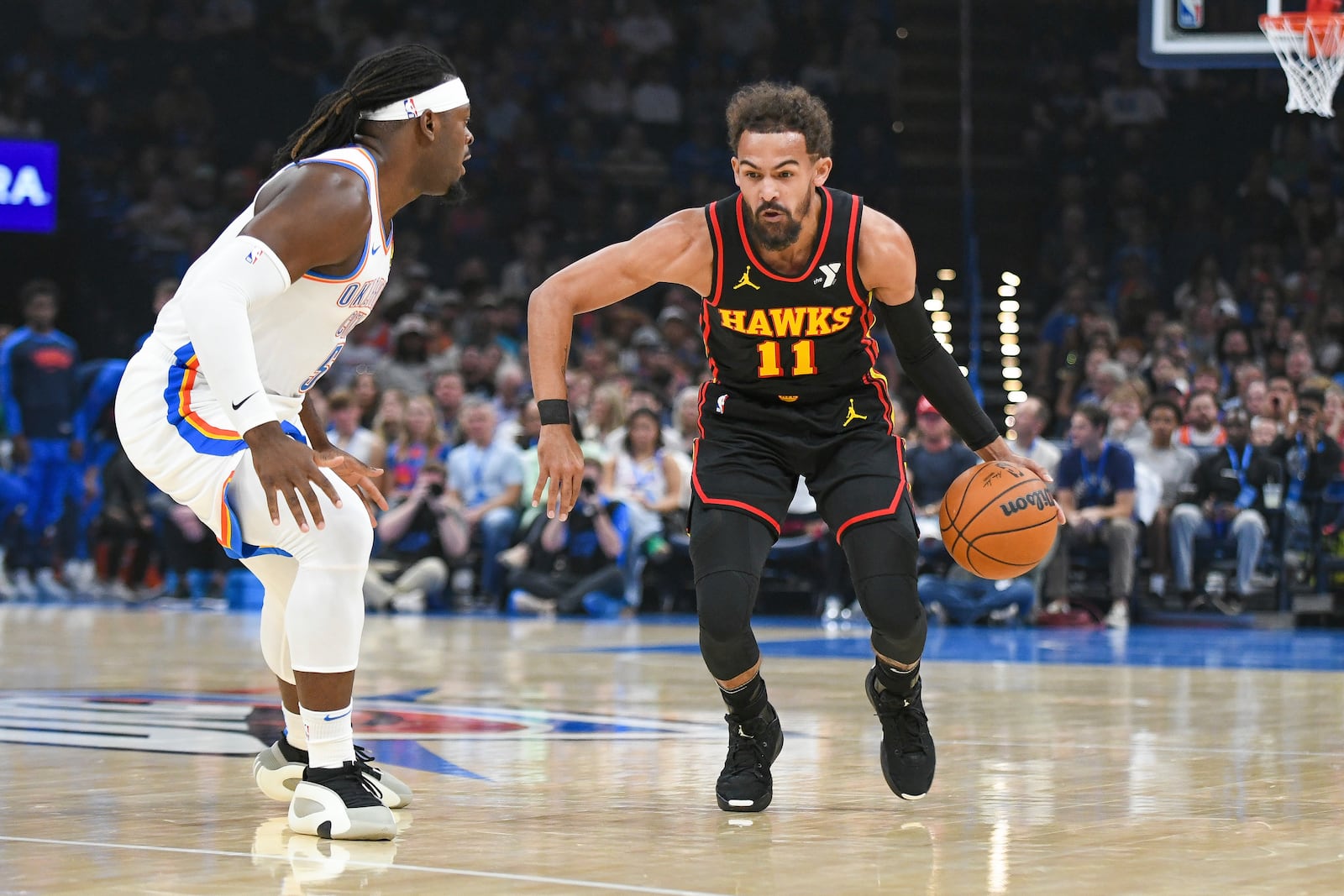 Atlanta Hawks guard Trae Young, right, looks for an opening past Oklahoma City Thunder guard Luguentz Dort, left, during the first half of an NBA basketball game, Sunday, Oct. 27, 2024, in Oklahoma City. (AP Photo/Kyle Phillips)