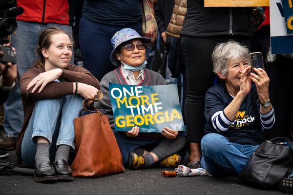 Supporters listen as  U.S. Sen. Raphael Warnock (D-Ga.) spoke by a mural of John Lewis in Atlanta, as Georgia’s Senate election headed to a runoff contest, on Nov. 10, 2022. (Nicole Craine/The New York Times)

