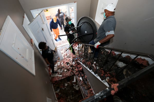 April Willars, left, watch as friends and family remove a table from their home that was damaged in a fire earlier this month, Thursday, Jan. 30, 2025, in Conyers, Ga. Chris and April Willars were on the property to salvage any items they could. They were also impacted by the Biolab fire and a tornado in the past year. (Jason Getz / AJC)