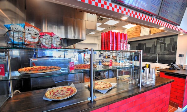 Freshly made pizza pies are on display at Pielands Sub & Slice's walk-up ordering area featuring individual slices for sale. (Chris Hunt for The Atlanta Journal-Constitution)